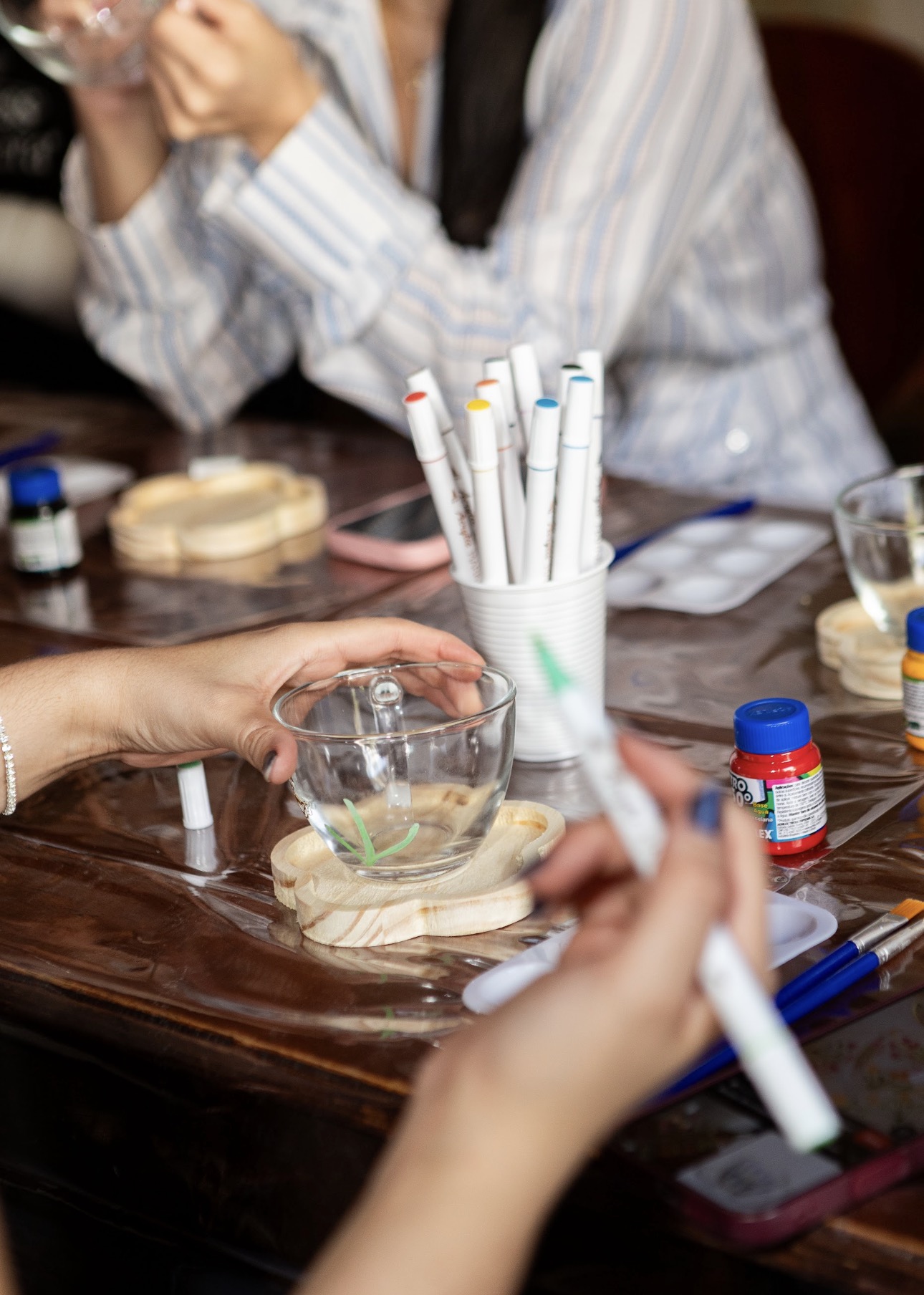 Participante pintando uma xícara durante a experiência artística